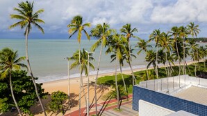 A beach view with palm trees and a clear sky. - Apart Praia de Cabo Branco por Carpediem (João Pessoa)