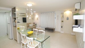 A modern kitchen with a glass dining table, white chairs, and a built-in oven. - Apart Praia de Cabo Branco por Carpediem (João Pessoa)