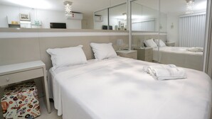 A modern hotel room with a large bed, a bedside table, a mirror, and a wardrobe. - Apart Praia de Cabo Branco por Carpediem (João Pessoa)
