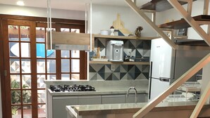 A modern kitchen with a central island, a built-in stove, and a stainless steel refrigerator. - Beautiful, cozy, and well-equipped - Geribá within walking distance! (Armação dos Búzios)