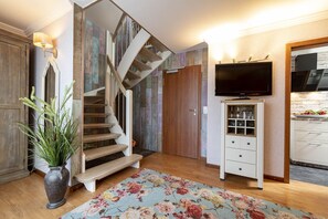 Stylish space with a wooden staircase, flat-screen TV, and floral-patterned rug.