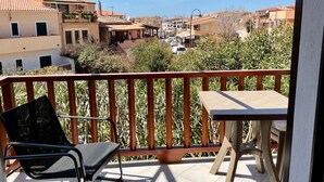 Un balcone con vista su una zona residenziale, una sedia e un tavolino.
