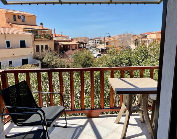 Un balcone con vista su una zona residenziale, una sedia e un tavolino.