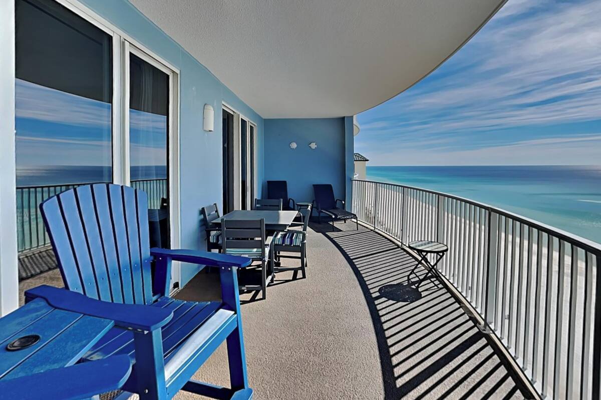 A balcony with a table and chairs, a view of the ocean, and a railing.