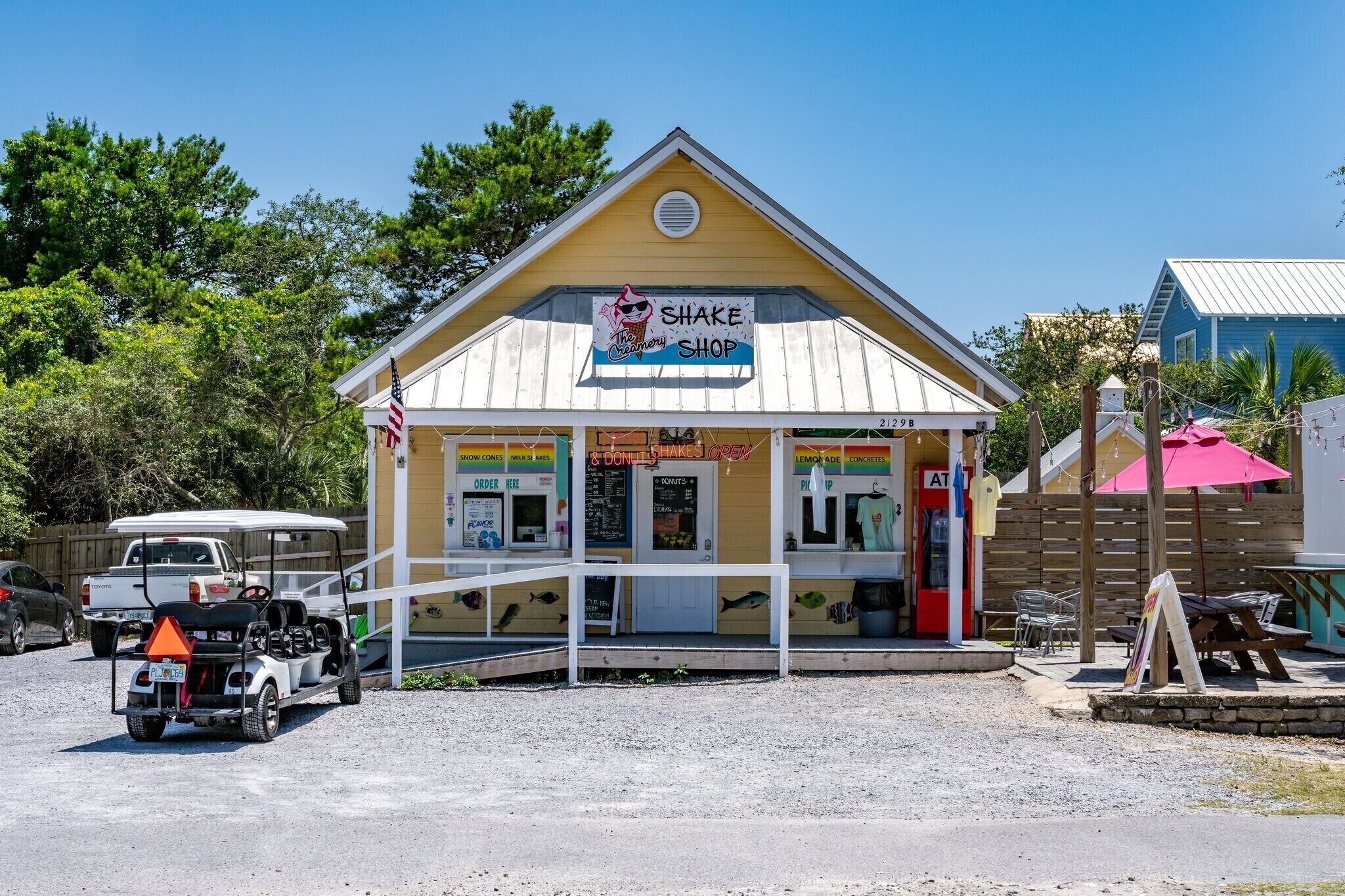A small building with a sign reading "Shake Shop" and a covered outdoor seating area.