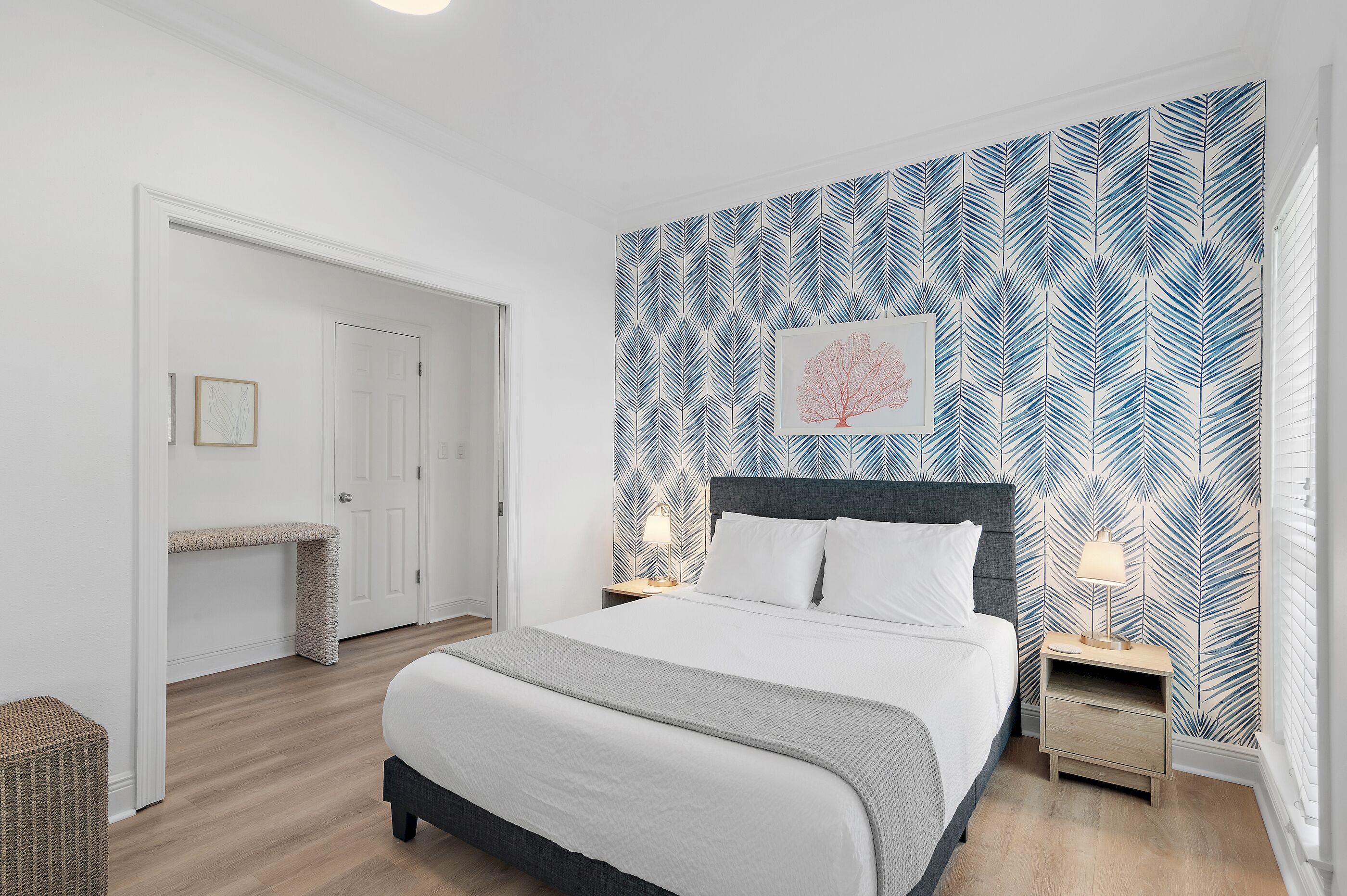Une chambre à coucher avec un lit, des tables de chevet, un banc et un papier peint à motifs.