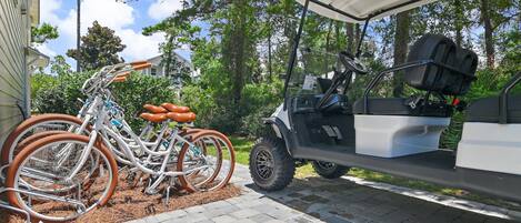 Un carrito de golf estacionado junto a una bicicleta con canasta.