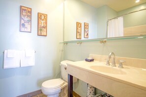 Ein Badezimmer mit Toilette, Waschbecken und drei gerahmten Kunstwerken an der Wand.