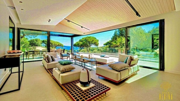 Ein modernes Wohnzimmer mit einer großen Glaswand, weißen Sofas und einem Couchtisch.