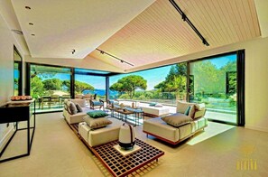 Un salon moderne doté d’une grande baie vitrée, de canapés blancs et d’une table basse.