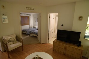Une chambre avec un lit, une télévision, une chaise et une commode.