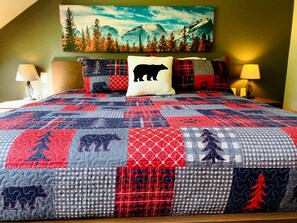 Une chambre à coucher avec un grand lit, un tableau représentant un paysage de montagne au-dessus du lit, et deux lampes de chevet.