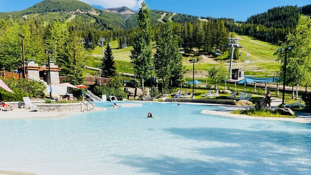Ein Schwimmbad mit Blick auf eine Seilbahn und Berge im Hintergrund.