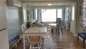 A dining area with a table and chairs, a bench, and a window with curtains.