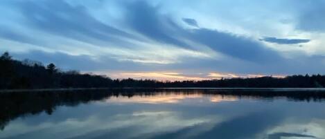 A calm lake at dusk with a clear reflection of the sky and trees.