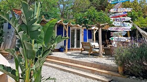 A rustic outdoor seating area with a wooden pergola, a small table, and a chair.