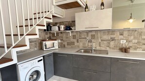 Une cuisine compacte équipée d’un lave-linge, d’un four à micro-ondes, d’un évier et d’un escalier.