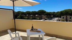 Un balcon avec une table dressée pour deux personnes, une bouteille de vin et quelques amuse-gueules.