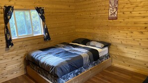 Une pièce de cabane en bois comprenant un lit, une fenêtre avec des rideaux et une décoration murale.