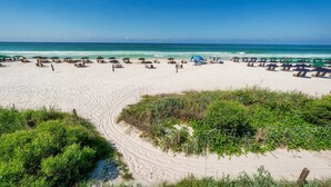 A beach with sun loungers and umbrellas, a clear sky, and a sandy shore. - Villa Rosé - Private pool near Rosemary Beach (Rosemary Beach)