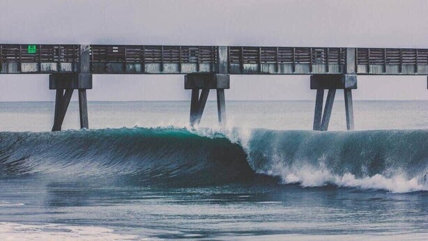 A pier extending into the ocean with waves crashing against it.