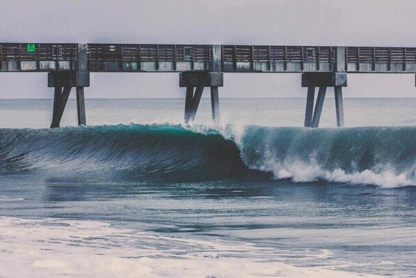 A pier with a wave crashing underneath.