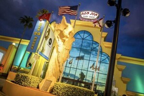 A building with a large glass facade, a sign reading "Ron Jon Surf Shop," and multiple American flags.