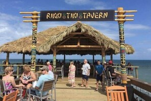 A beachside restaurant with a thatched roof and a sign reading "Rikki Tiki Tavern".