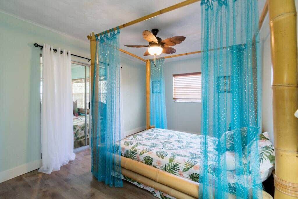 Een kamer met een hemelbed, een plafondventilator en dunne gordijnen.