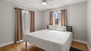 A bedroom with a bed, a ceiling fan, and curtains on the windows. - Spacious 5BR Near Bishop Arts - 5 Min Drive! (Dallas)