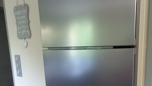 Un refrigerador Bosch de acero inoxidable en una cocina con paredes de colores claros y suelo de madera.