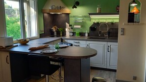 Una cocina moderna con una isla central, armarios blancos y una pared verde decorativa.