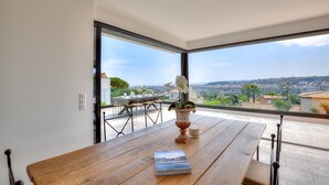 Un espace repas moderne avec une table en bois, un vase de fleurs blanches et un livre intitulé « Californie ».