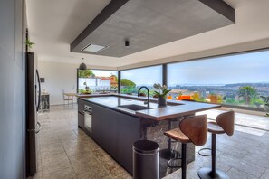 A modern kitchen with a large island, a sink, and a view of the city.