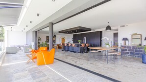 Un vaste espace de vie comprenant une cuisine moderne, un coin salon et une grande fenêtre laissant entrer la lumière naturelle.