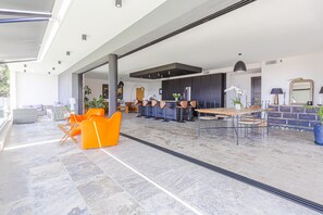 A spacious living area with a modern kitchen, seating arrangements, and a large window providing natural light.