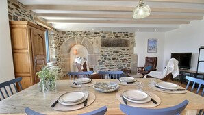 A dining area with a stone wall, wooden cabinets, and a table set for four. - Des deux plages - PLERIN (PLERIN)