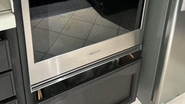 Een rvs Whirlpool oven met glazen deur, ingebouwd in een keukenkast.