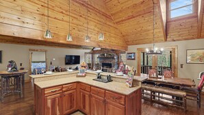 A spacious kitchen with wooden cabinets, a large island, and hanging pendant lights.