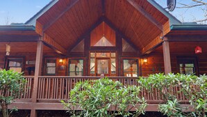 A wooden cabin with a gabled roof, a covered porch, and a satellite dish. - Vintage Luxury Creekside Cabin ~ King Bed, Hot Tub, Fire Pit & Game Room, Dog Ok (Hiawassee)