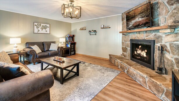 A cozy living room with a stone fireplace, a comfortable sofa, a coffee table, and a world map on the wall.
