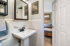 A bathroom with a white sink, a mirror, and a framed sign on the wall. - Gatlinburg. Downtown. 2br (Gatlinburg)