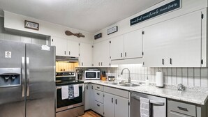 A modern kitchen with stainless steel appliances, white cabinets, and a granite countertop.
