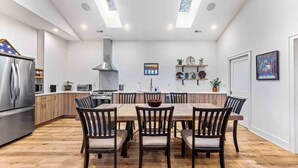 A modern kitchen with a central island, wooden chairs, and a stainless steel refrigerator. - Little Bee Woods (Swannanoa)