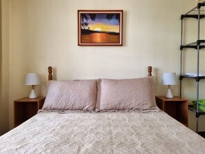 Relax in a cozy space with a large bed, two bedside tables, and a framed painting above.
