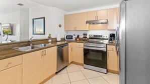 A modern kitchen with stainless steel appliances, wooden cabinets, and a granite countertop. - Cozy 3BR/2BA  King Bed  Free Parking  Pet-Friendly (Miami)