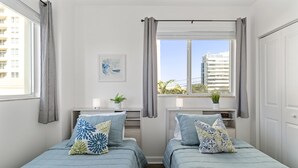 A bedroom with two beds, a window with curtains, a bedside table with a plant, and a wall-mounted clock. - Cozy 3BR/2BA  King Bed  Free Parking  Pet-Friendly (Miami)