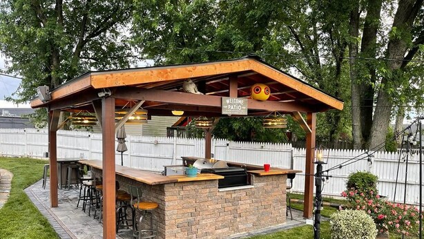 A patio with a barbecue grill, seating area, and a 'Welcome to Patio' sign. - The Santi Paradise (Glen Burnie)