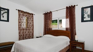 A bedroom with a wooden bed, two bedside tables, a window with curtains, and framed artwork on the walls. - Villa Mariposa, Lagos beach, private pool (Lagos)
