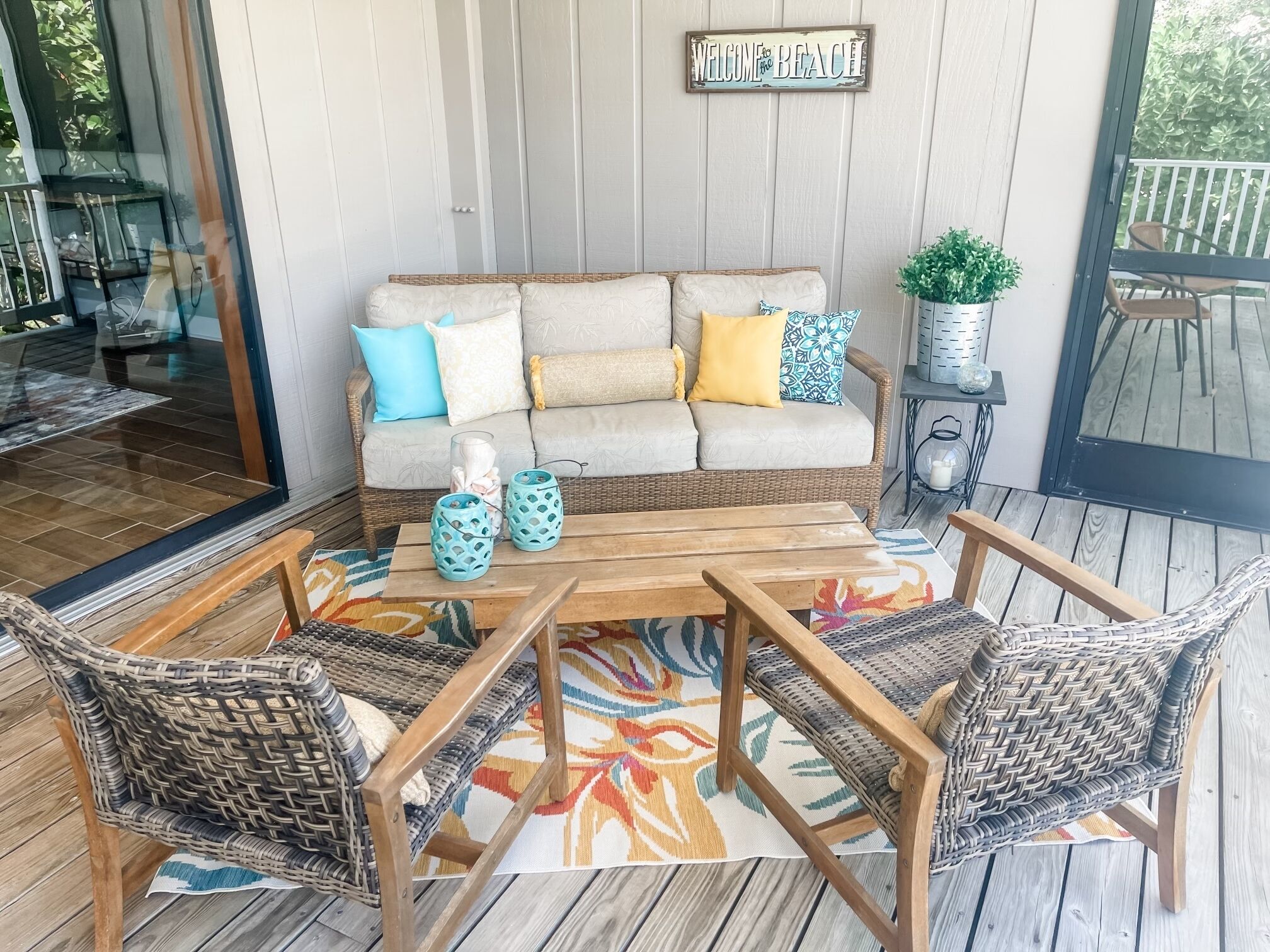 A cozy outdoor seating area with a wicker sofa, two chairs, and a wooden table.